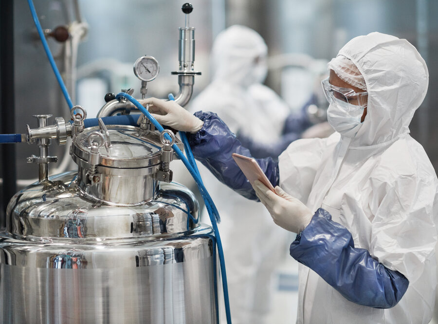 female worker wearing protective suit while operating equipment at modern chemical plant, copy space